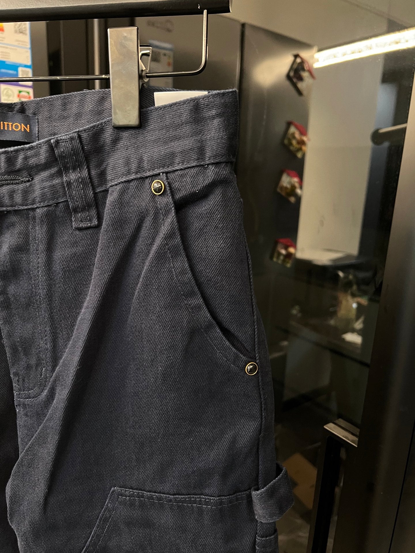 Dark blue denim cargo pants with button fly, pleated front, and large pocket