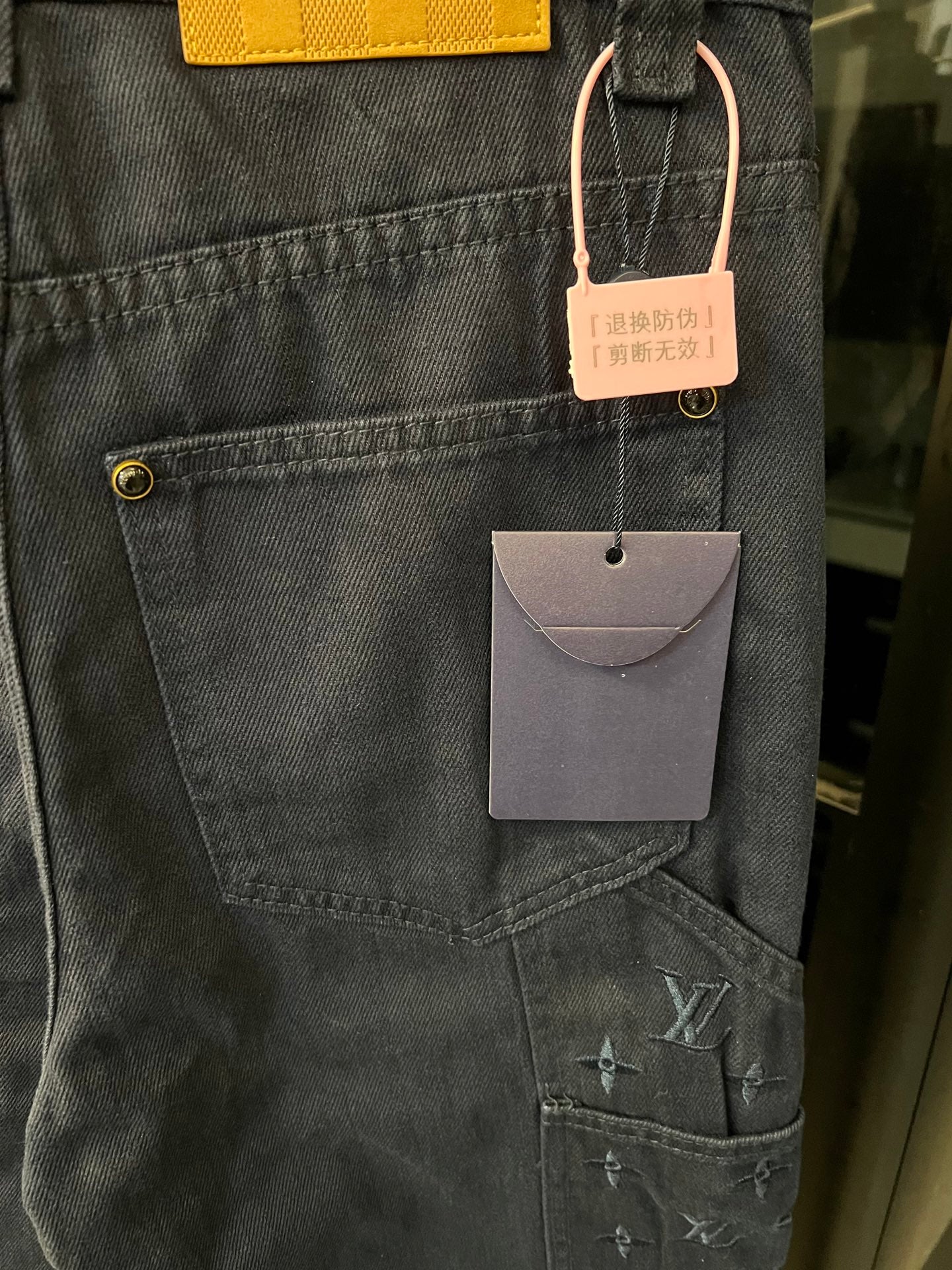 Dark blue denim cargo pants with front patch pocket and hanging product tags