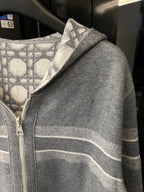 Grey zip-up hoodie side view with monogram shoulder print and striped sleeve band