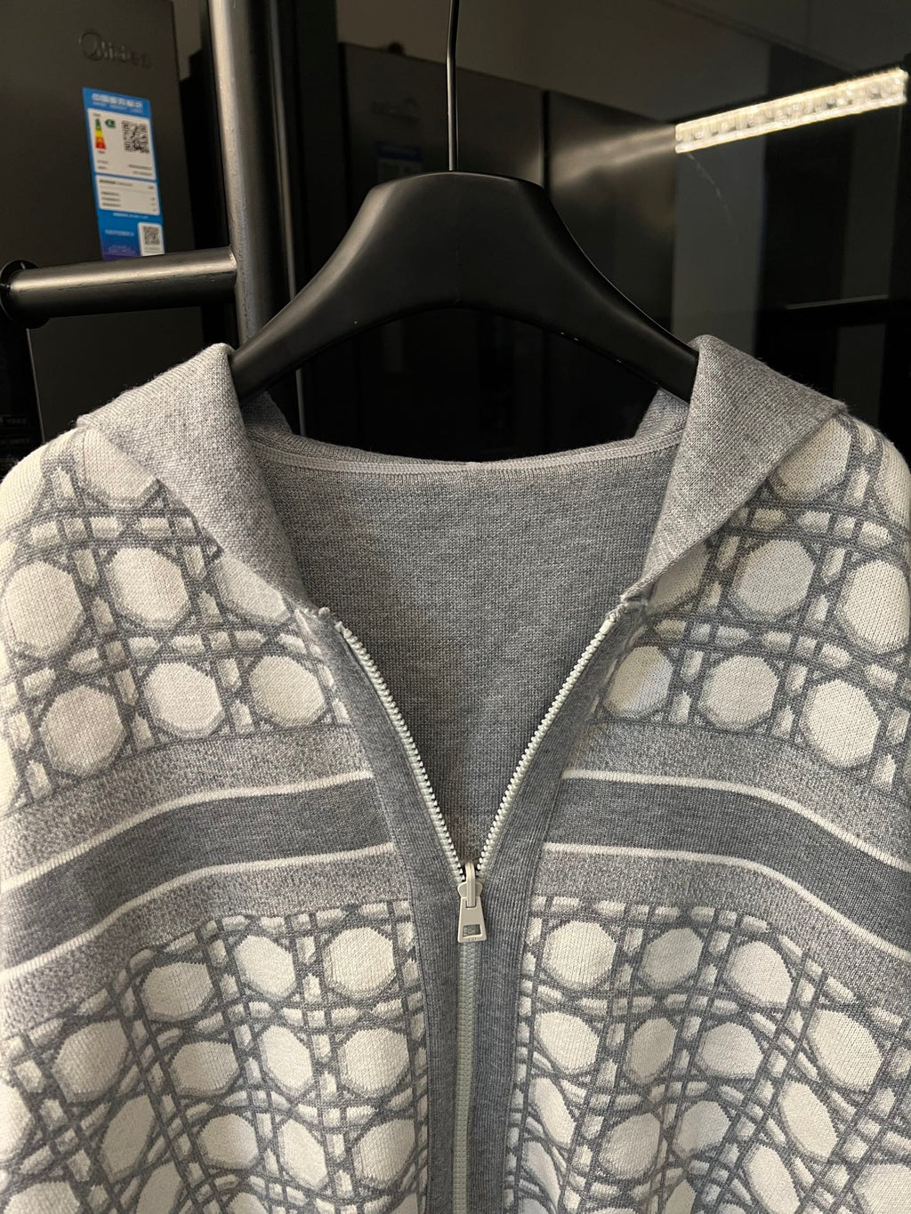 Grey zip-up hoodie front close-up with monogram sleeves and horizontal striped bands