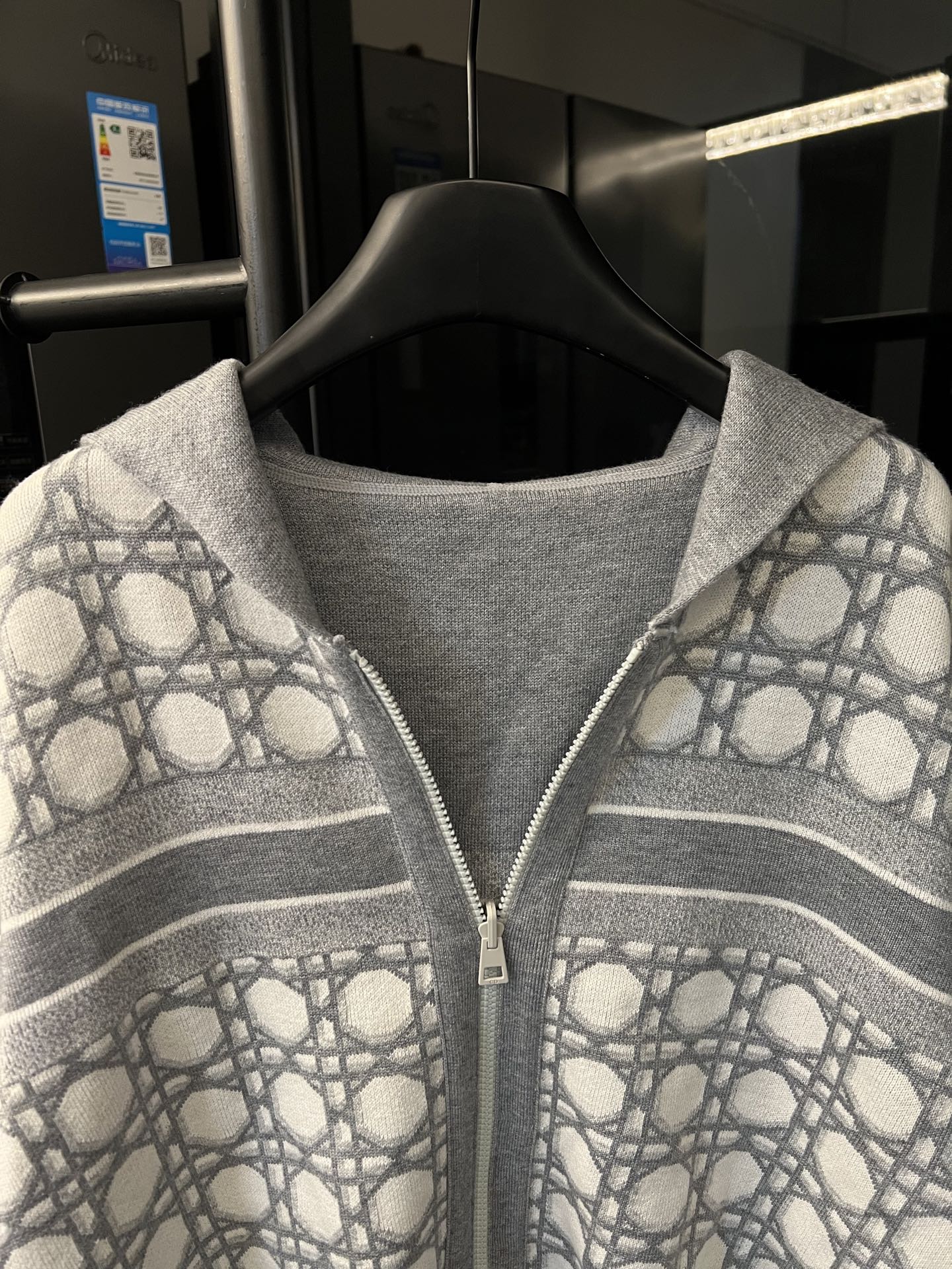Grey zip-up hoodie front close-up with monogram sleeves and horizontal striped bands