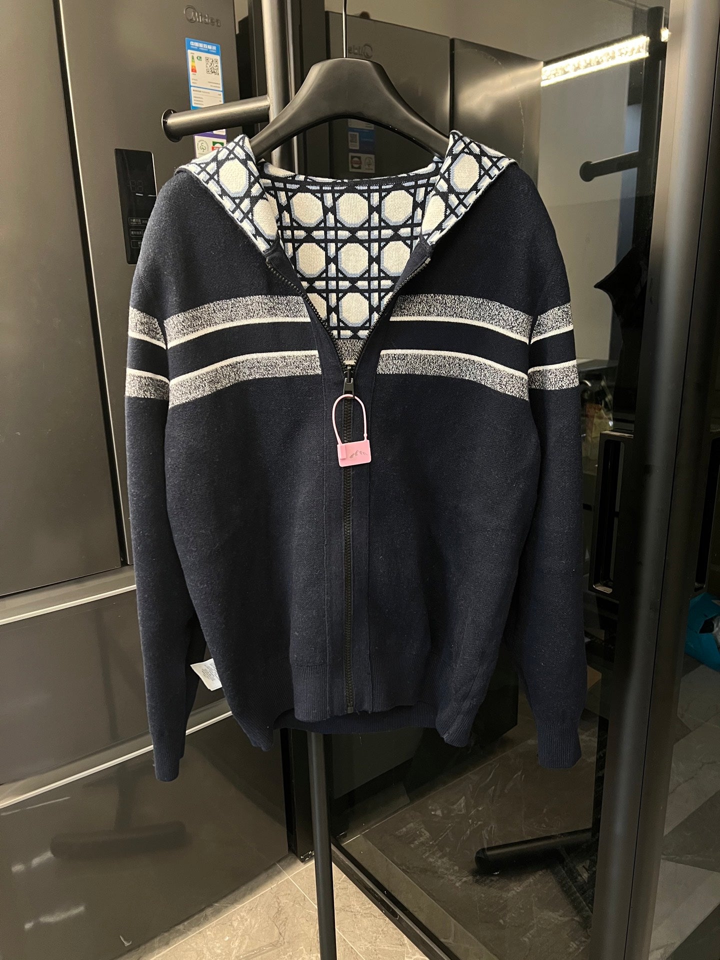 Dark hooded zip-up jacket with white stripe banding across the chest and arms