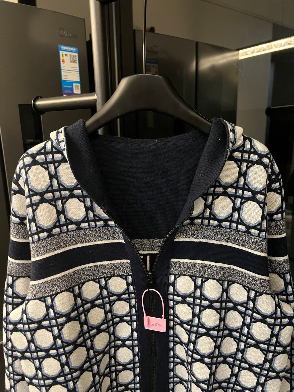 Front view hooded zip-up jacket with navy hood lining and white lattice panels on sleeves