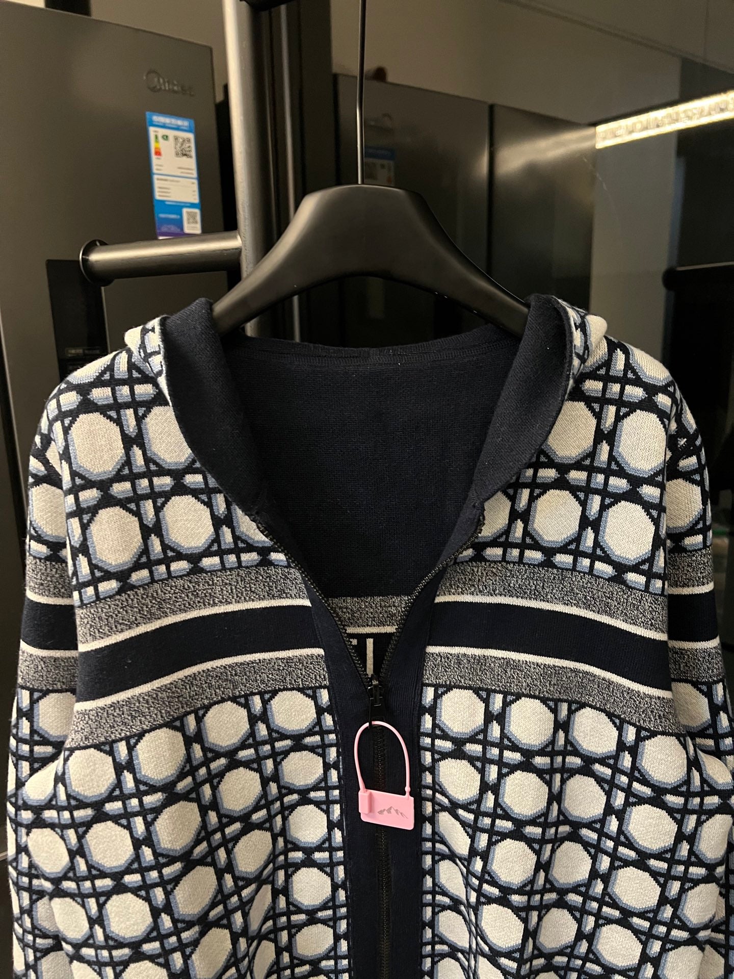 Front view hooded zip-up jacket with navy hood lining and white lattice panels on sleeves