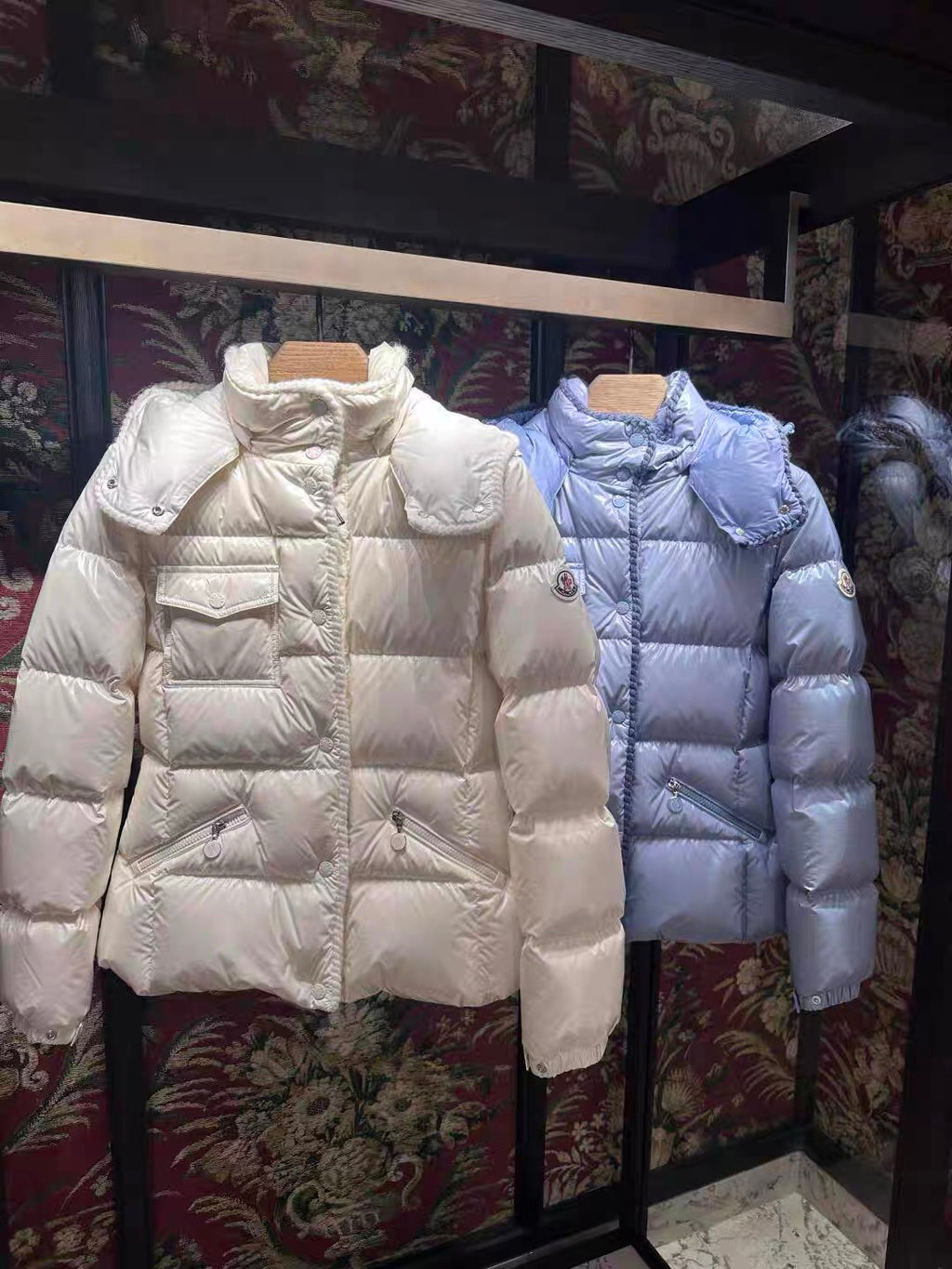 Moncler long hooded puffer jackets, white and light blue, side-by-side on stands