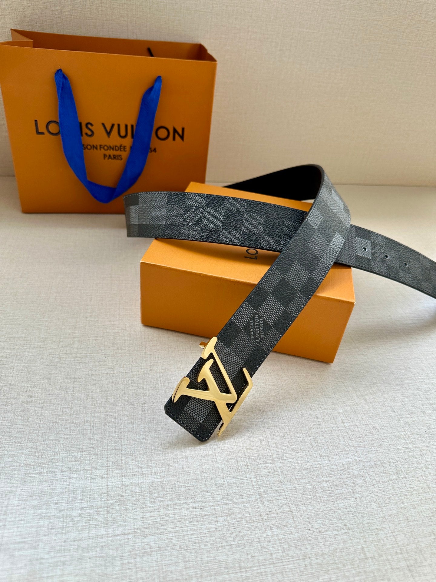 Louis Vuitton Damier check belt with gold-toned LV buckle and dark gray strap