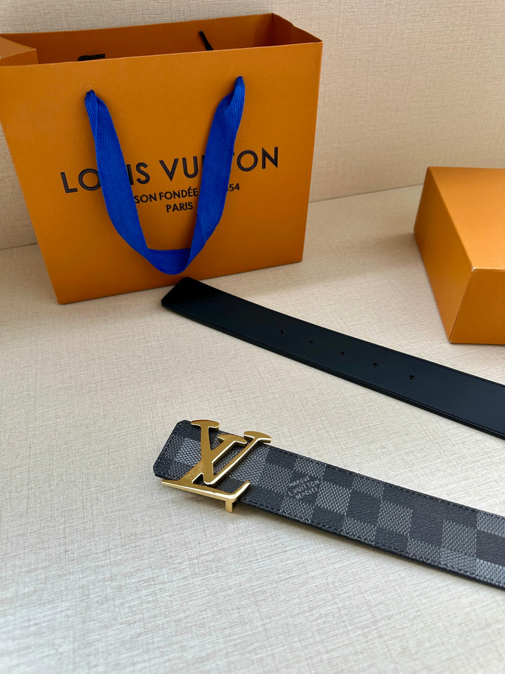 Louis Vuitton Damier check belt with gold-toned LV buckle, dark gray strap