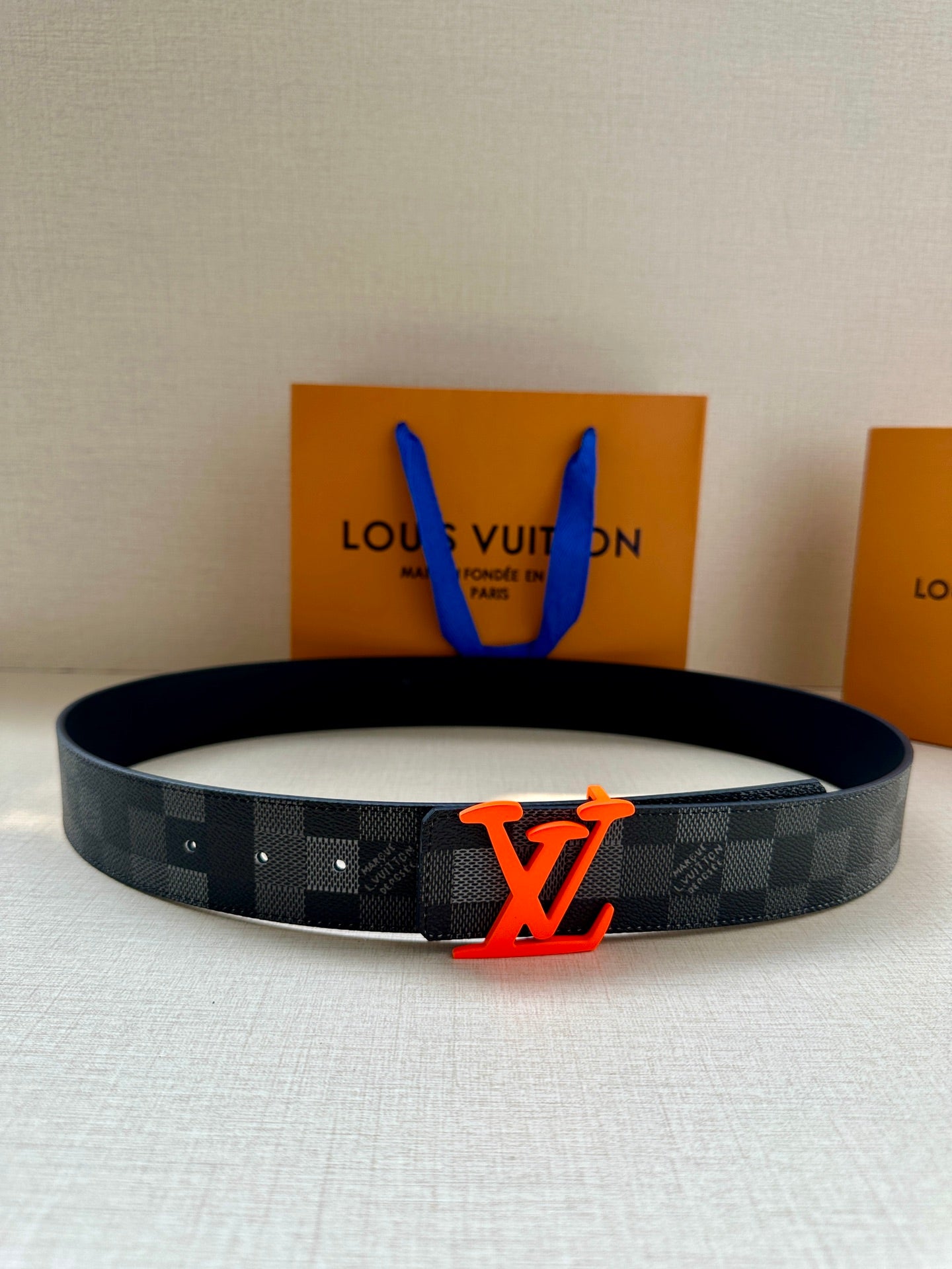 Louis Vuitton belt with dark check pattern and red-orange LV logo buckle
