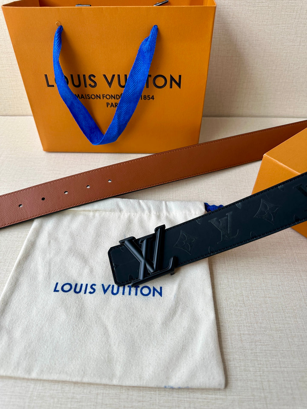 Louis Vuitton belt laid flat with dark monogram strap and black metal buckle