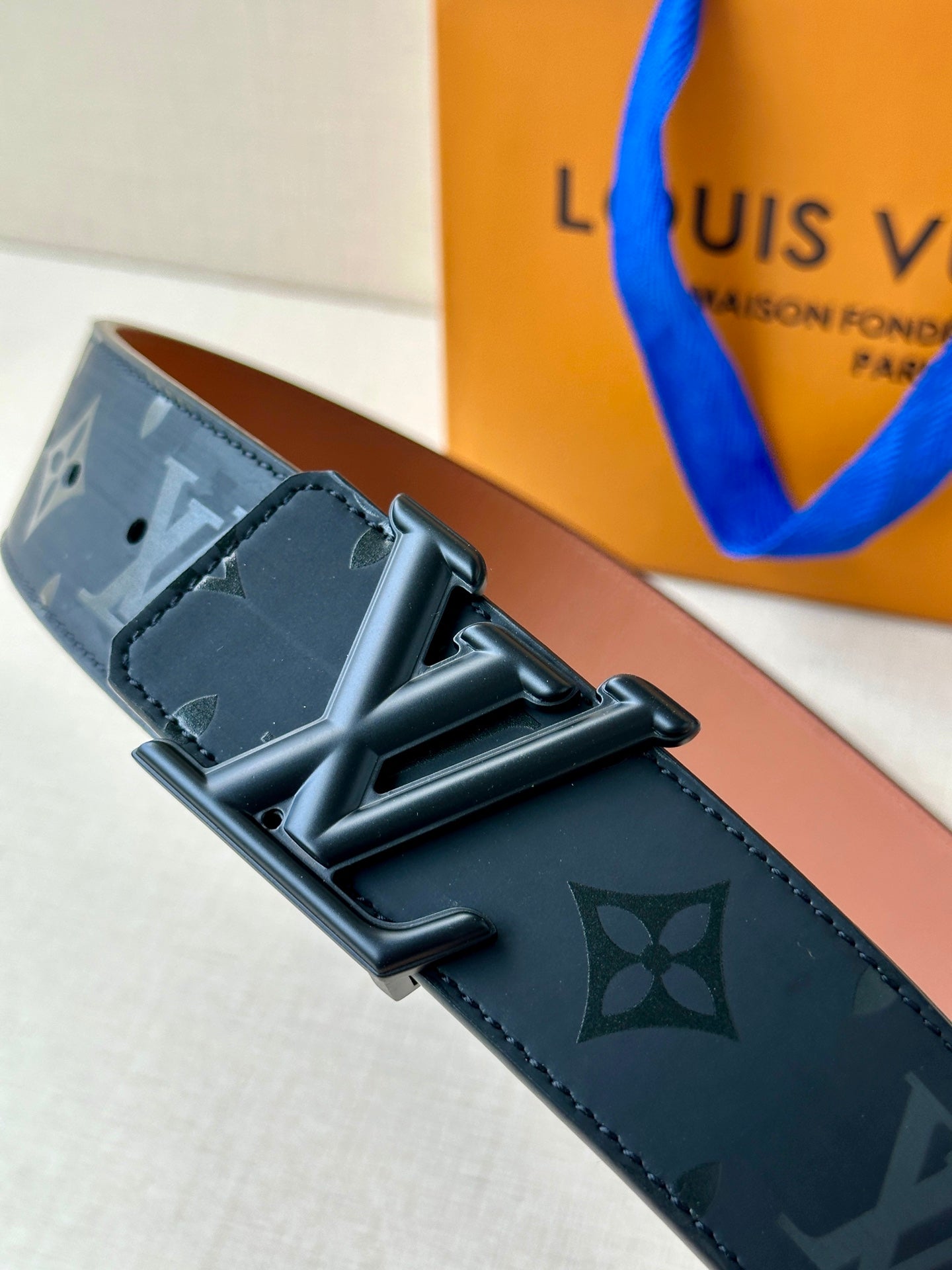 Louis Vuitton belt close-up: dark monogram strap, black buckle with bar detail