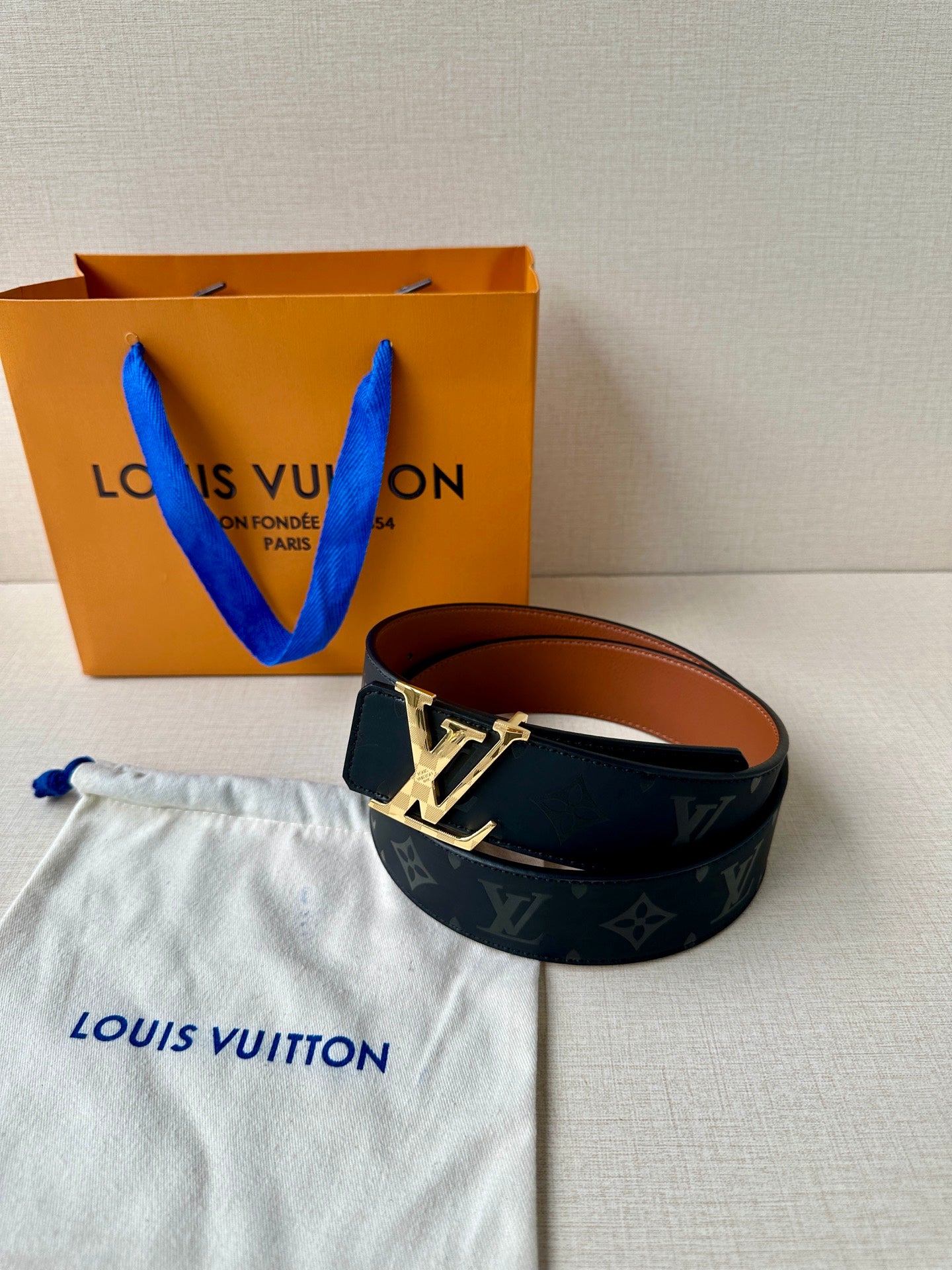 Louis Vuitton belt with dark navy monogram strap and gold-tone "LV" buckle