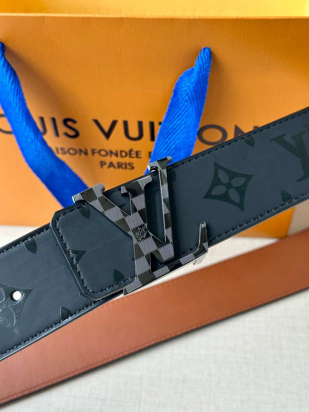 Louis Vuitton belt detail: dark navy monogram strap with silver buckle and keeper