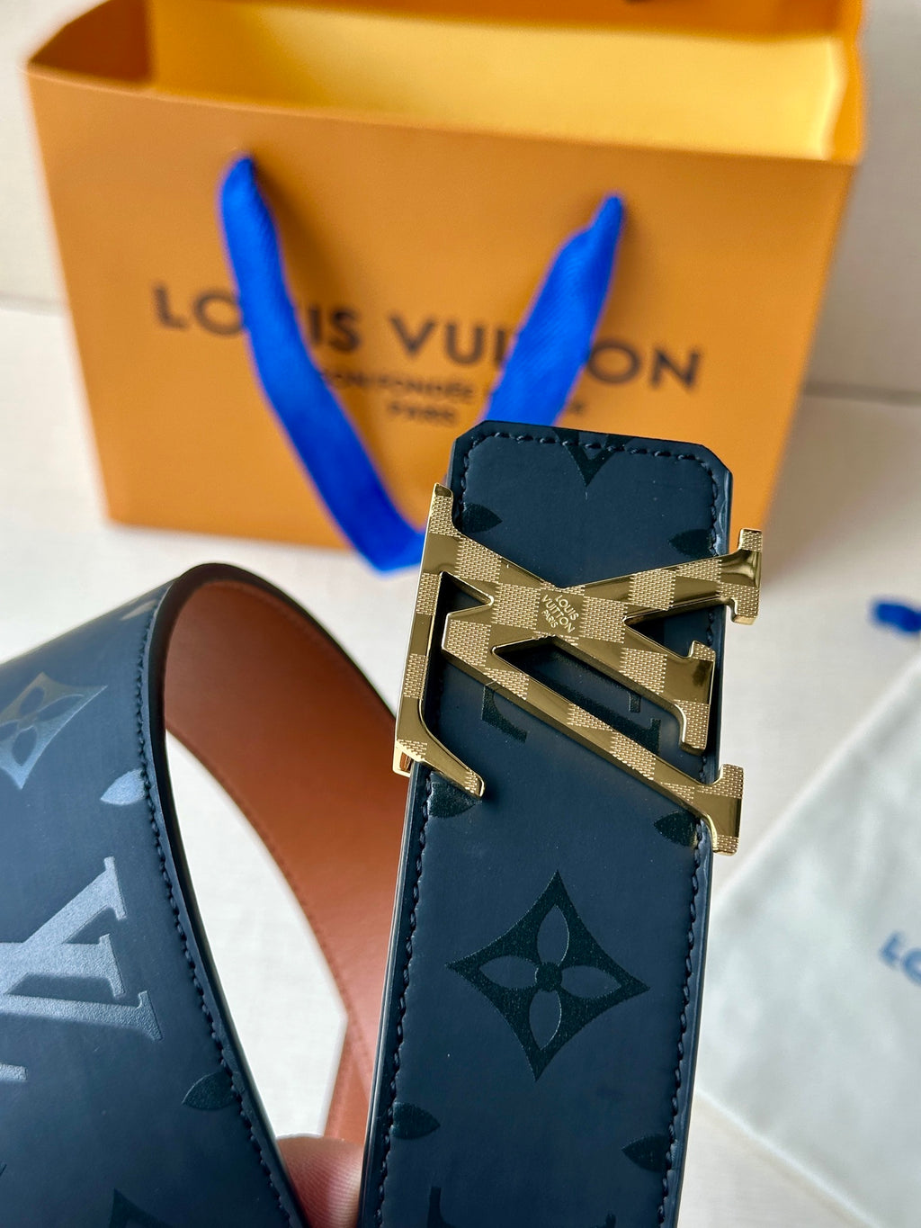 Louis Vuitton belt buckle close-up on dark navy monogram strap with silver/gold hardware