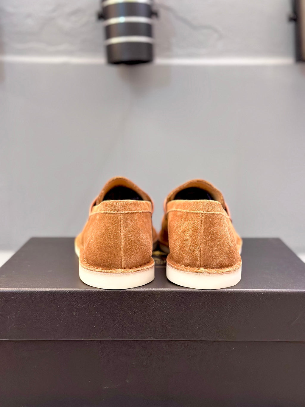 Tan suede loafers on black box, view of back heels and sole