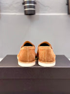 Tan suede loafers on black box, view of back heels and sole