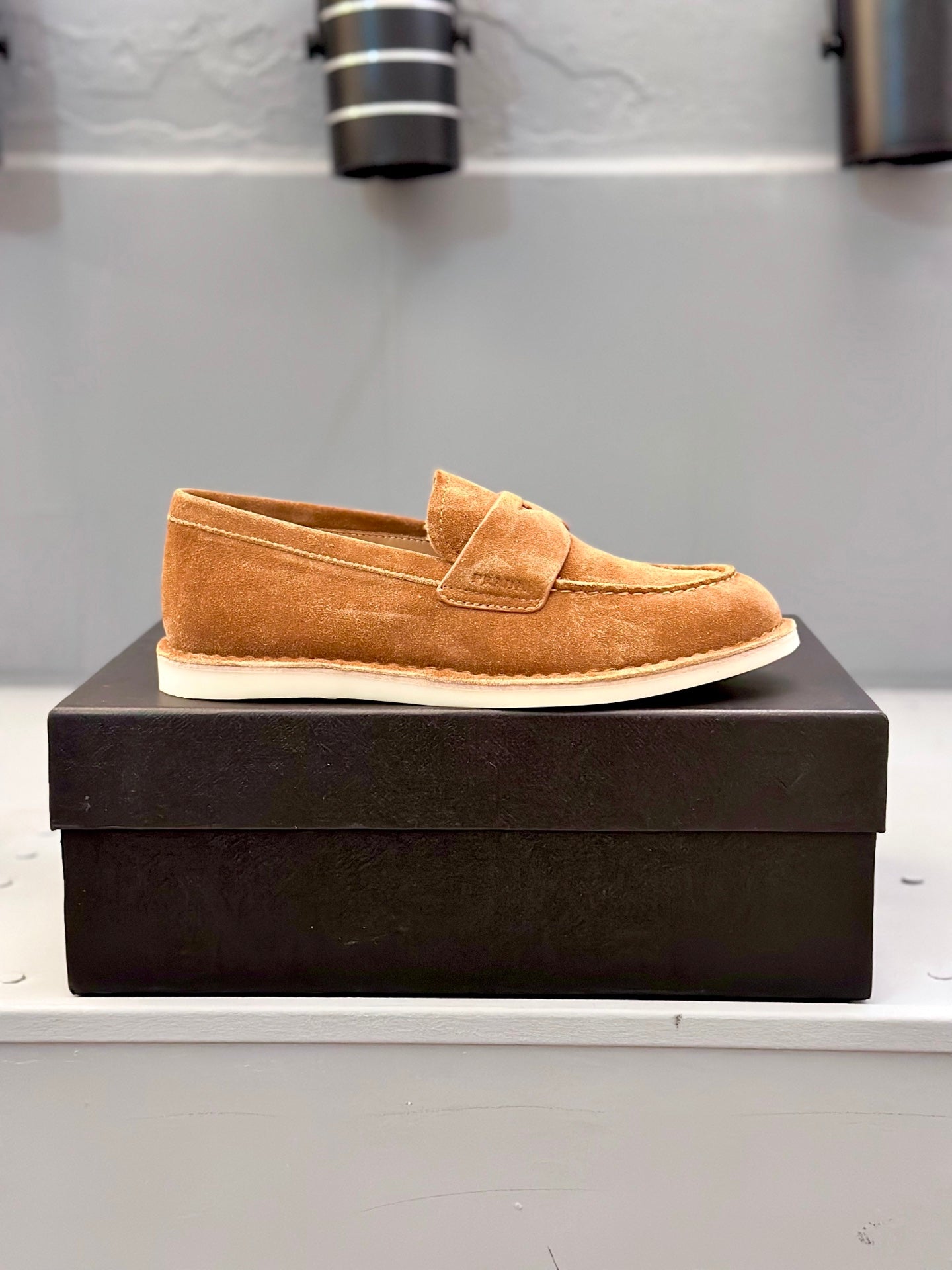 Tan suede slip-on loafer on black box with top strap vamp