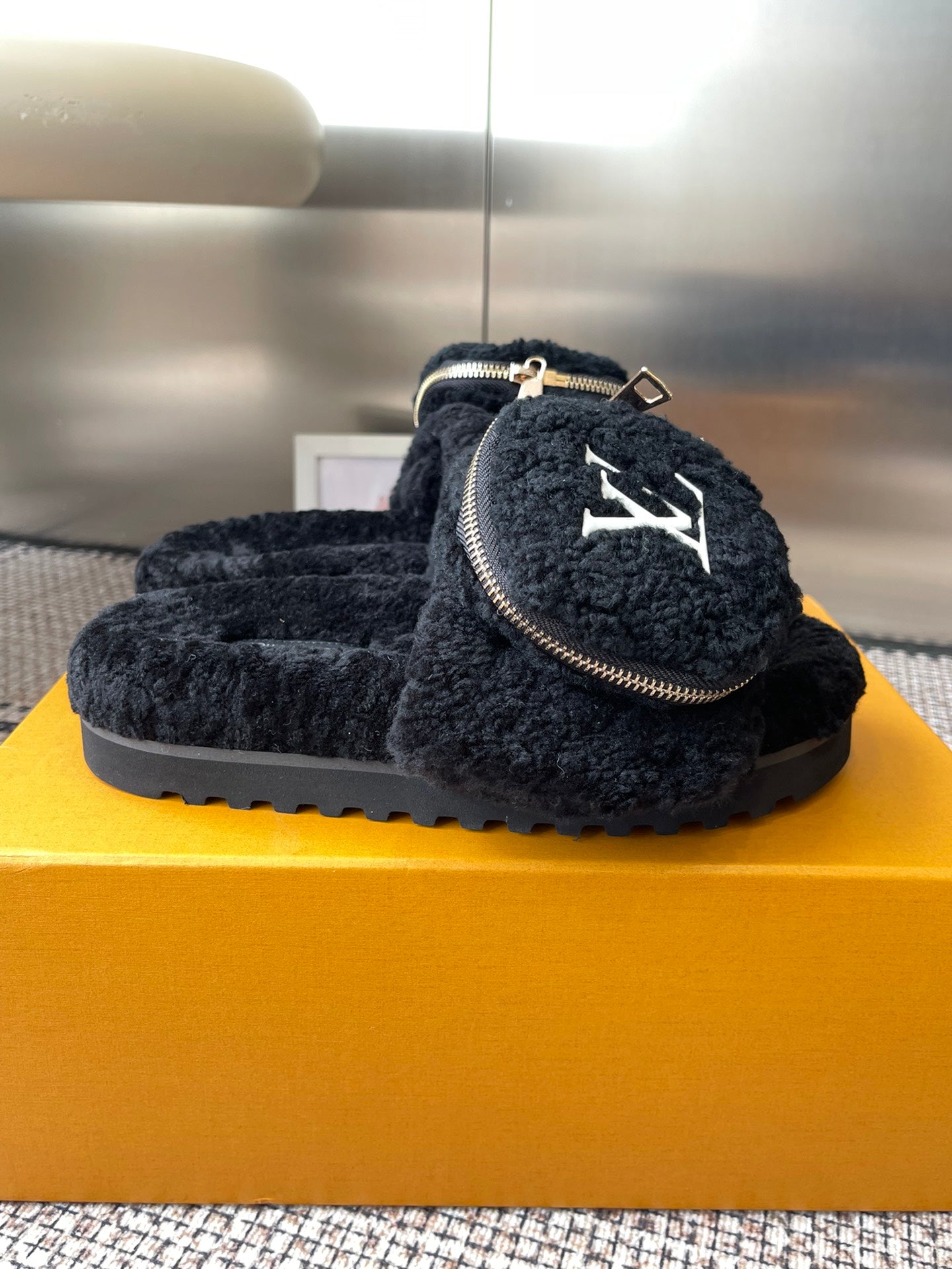 Louis Vuitton black sherpa slides, side view with zipper trim and LV logo