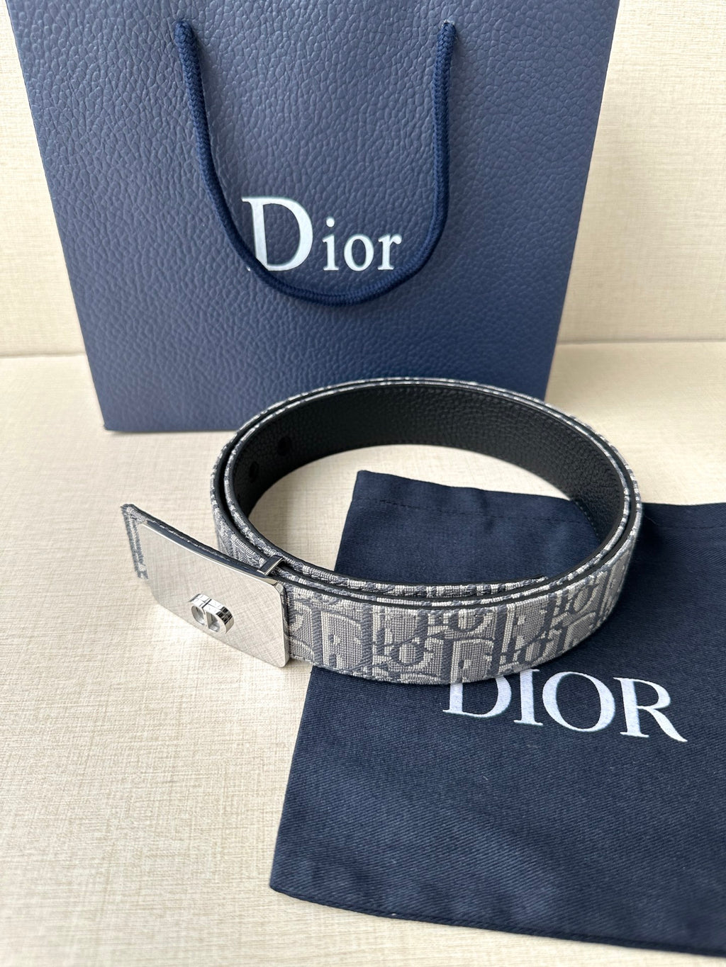 Dior belt with gray monogram strap, black edge trim, and gold-tone buckle