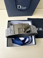 Dior belt with gray monogram strap and gold buckle, laid across box inserts