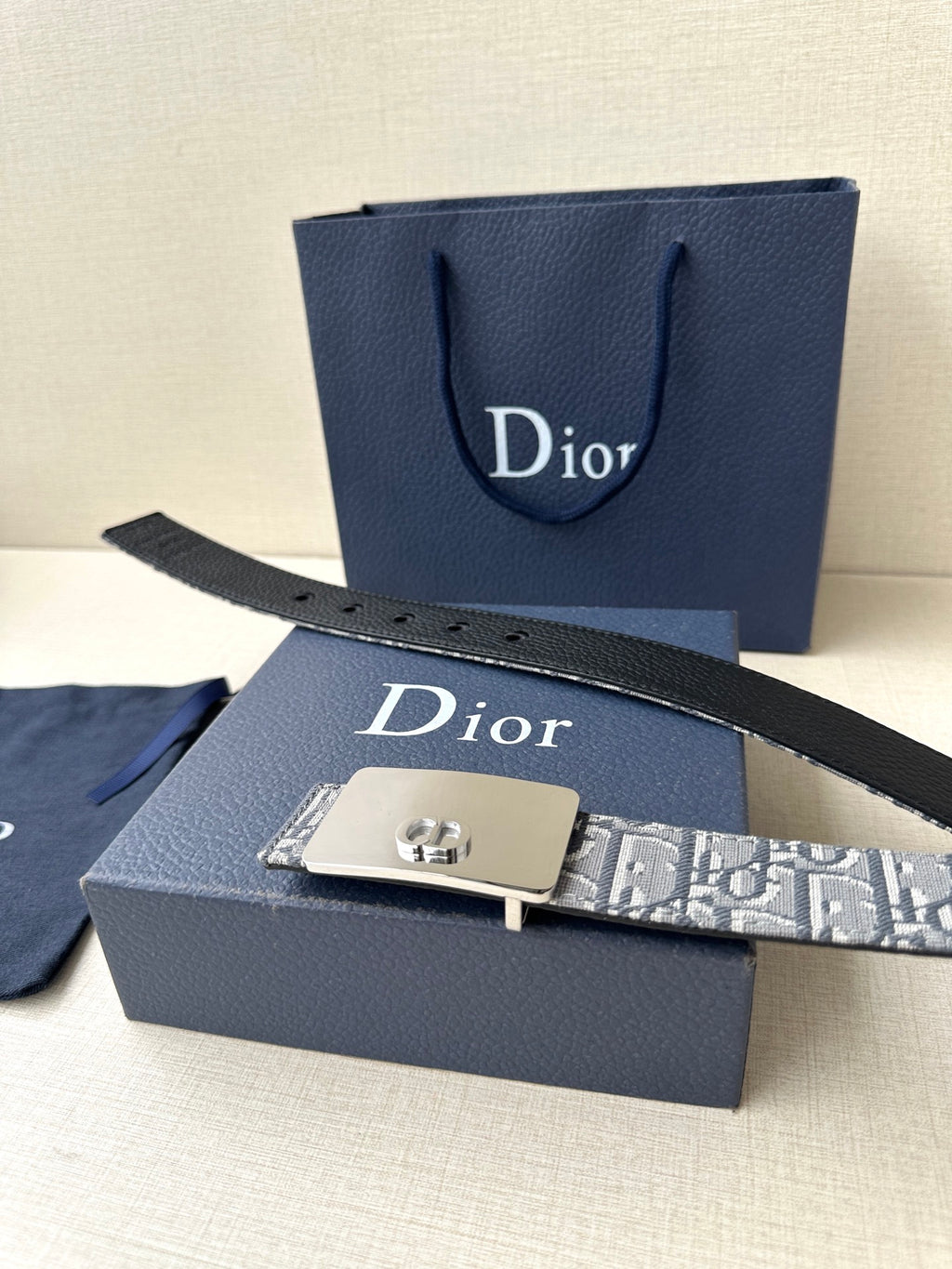 Dior belt close-up: black strap edge, gray monogram pattern, and silver buckle