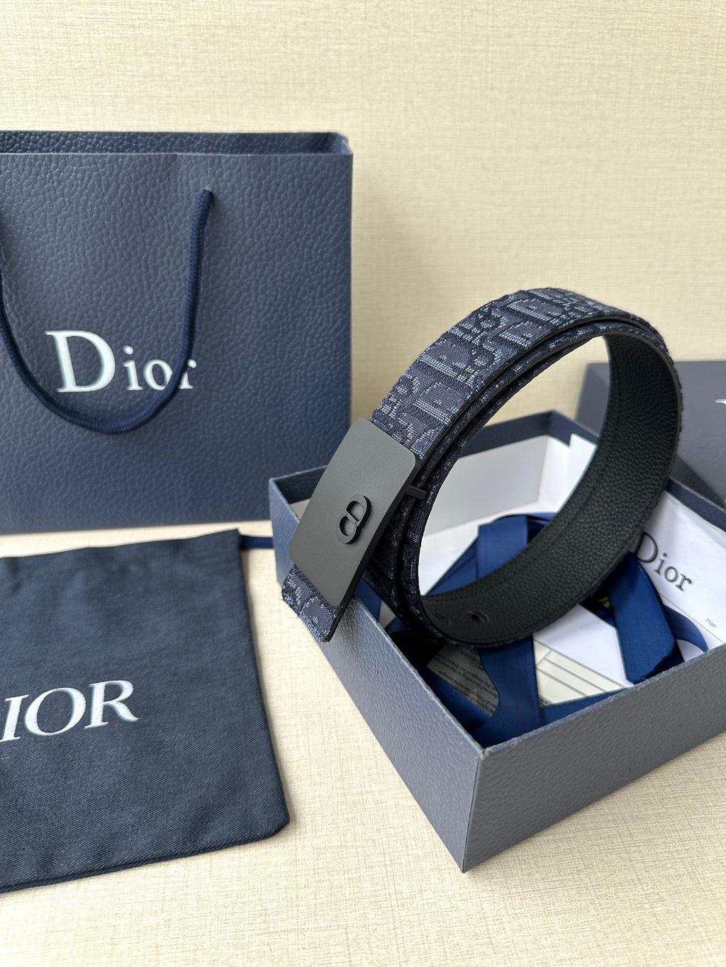 Dior belt with navy logo strap and matte black buckle, belt end detail