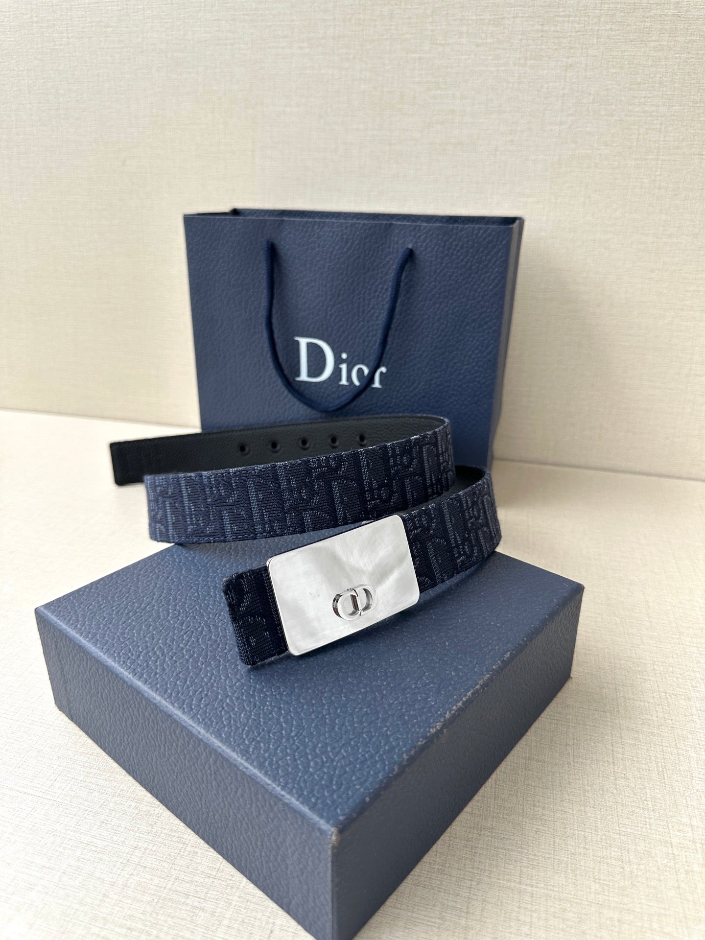 Dior belt on box: navy patterned strap with silver-tone CD buckle and strap holes.