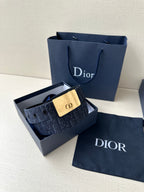 Dior belt in open box: navy patterned strap with gold-tone buckle plaque and strap holes.