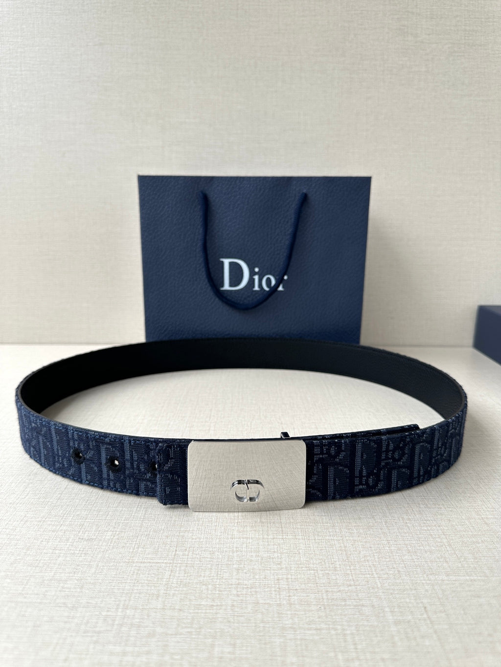 Dior belt in navy blue with dark pattern, silver-tone rectangular buckle, holes on strap.