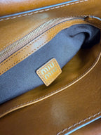 Brown MiuMiu bag interior pocket with blue fabric lining and logo patch