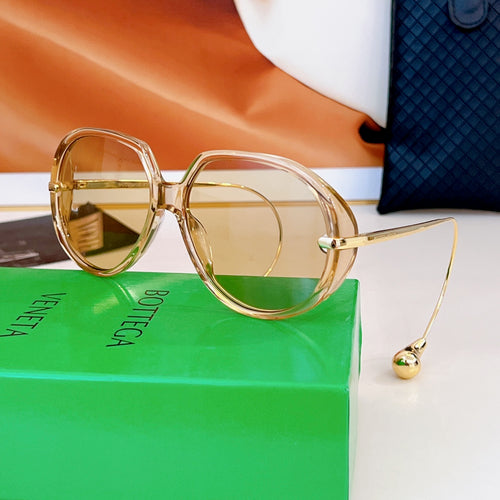 Bottega Veneta sunglasses with gold frames and amber-tinted lenses