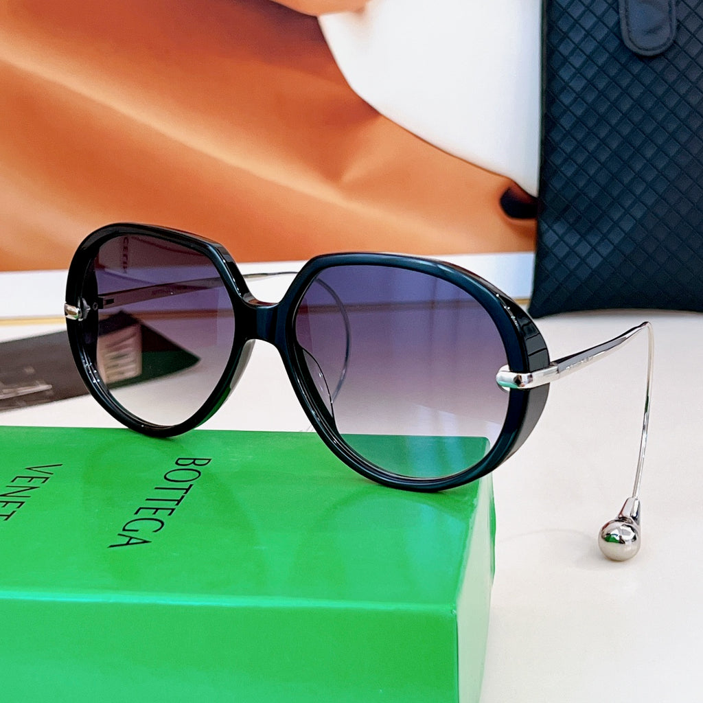 Sunglasses with dark frames and purple-tinted lenses, gold bridge hardware