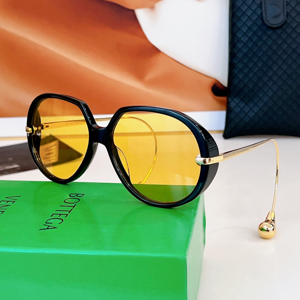 Sunglasses with black frames and yellow-gold tinted lenses, gold temples