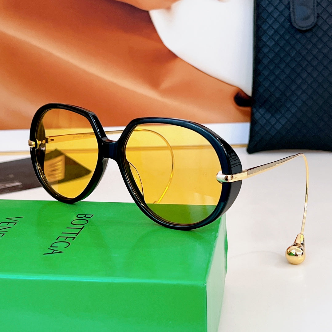 Sunglasses with black frames and yellow-gold tinted lenses, gold temples