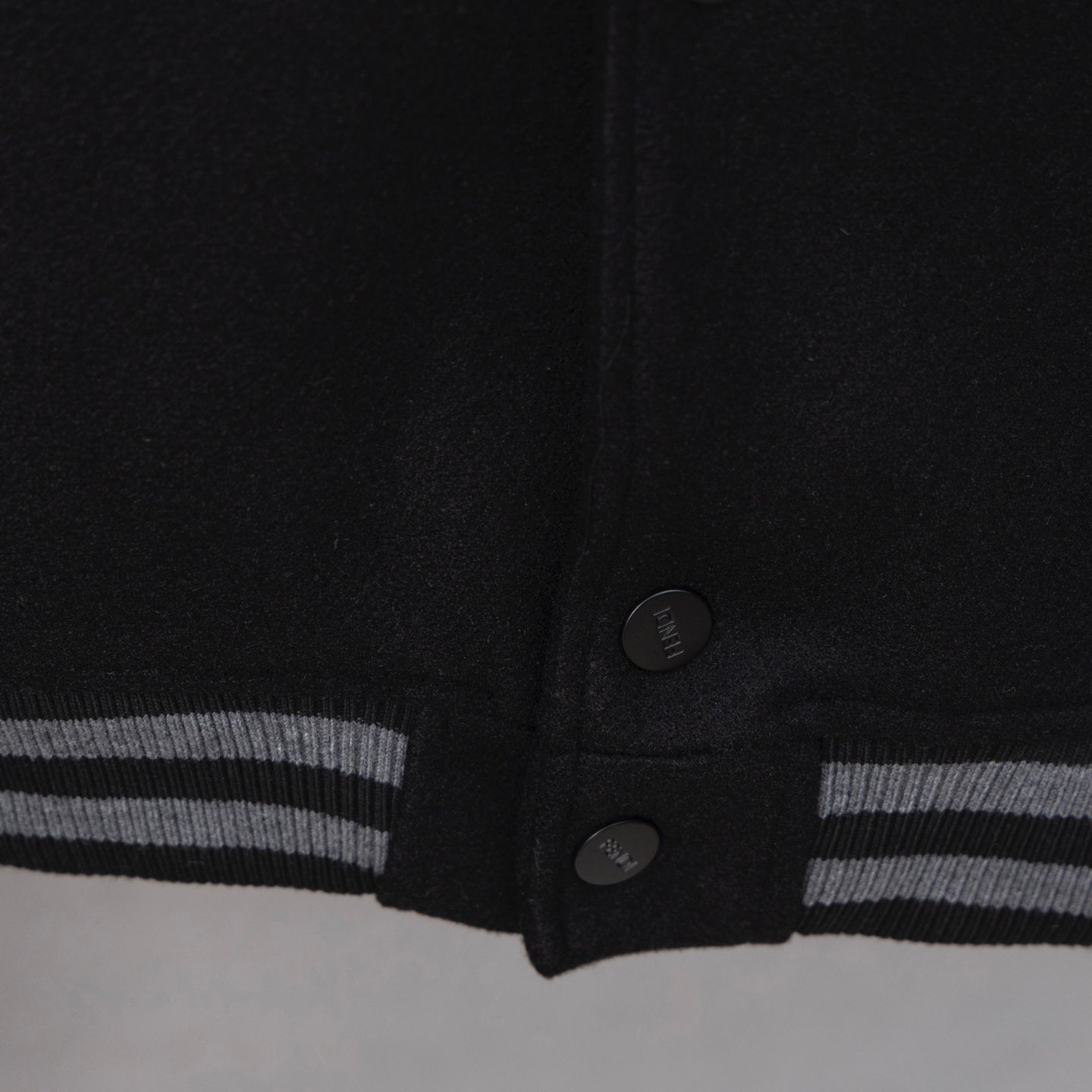 Black jacket hem with snap buttons and striped ribbed cuff