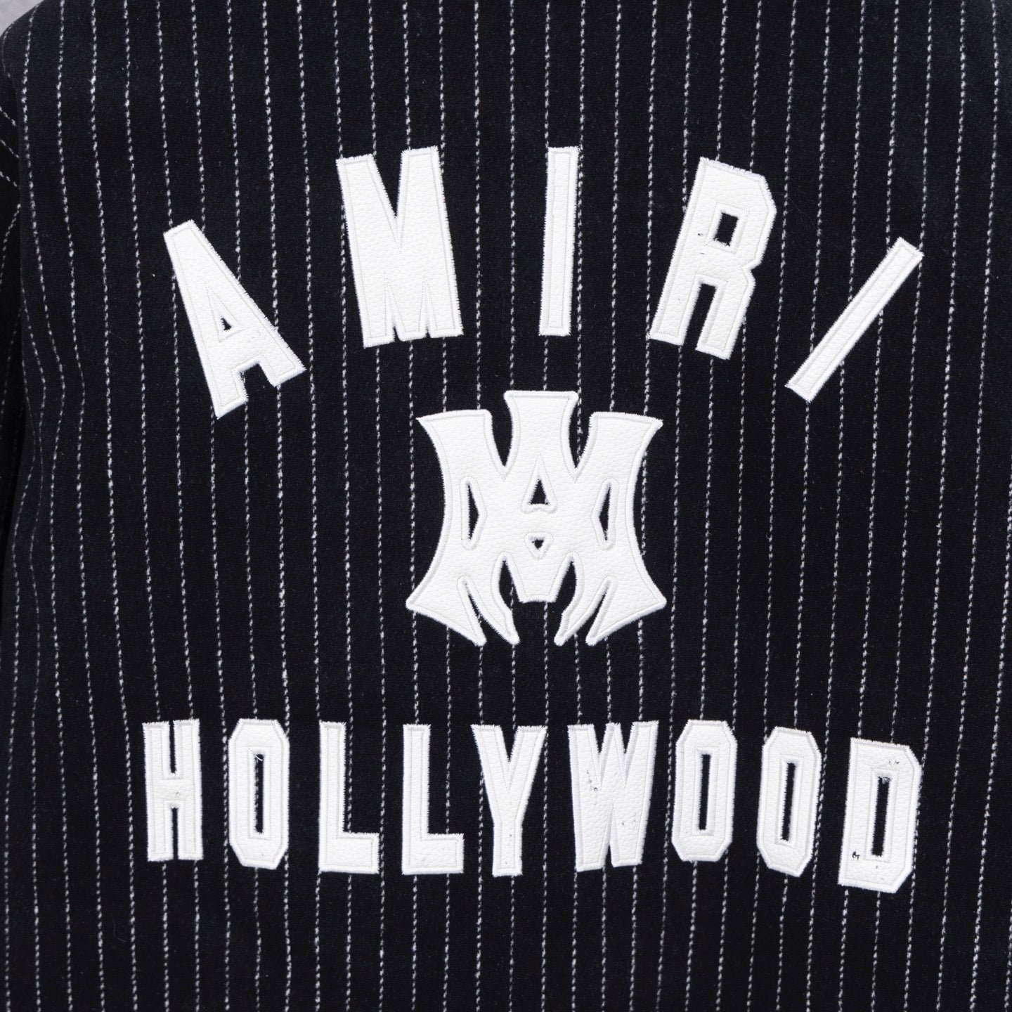 Pinstripe varsity jacket back graphic with 'AMIRI' and 'HOLLYWOOD' text