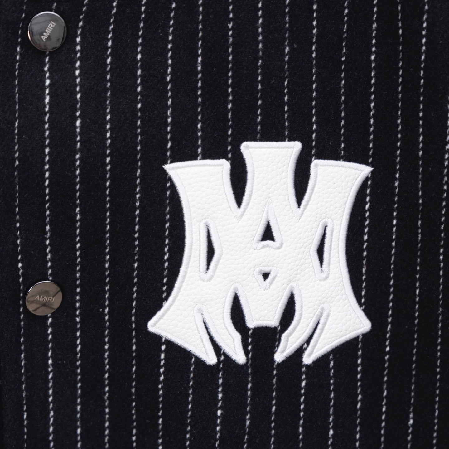 White AMIRI logo patch on dark pinstripe varsity jacket
