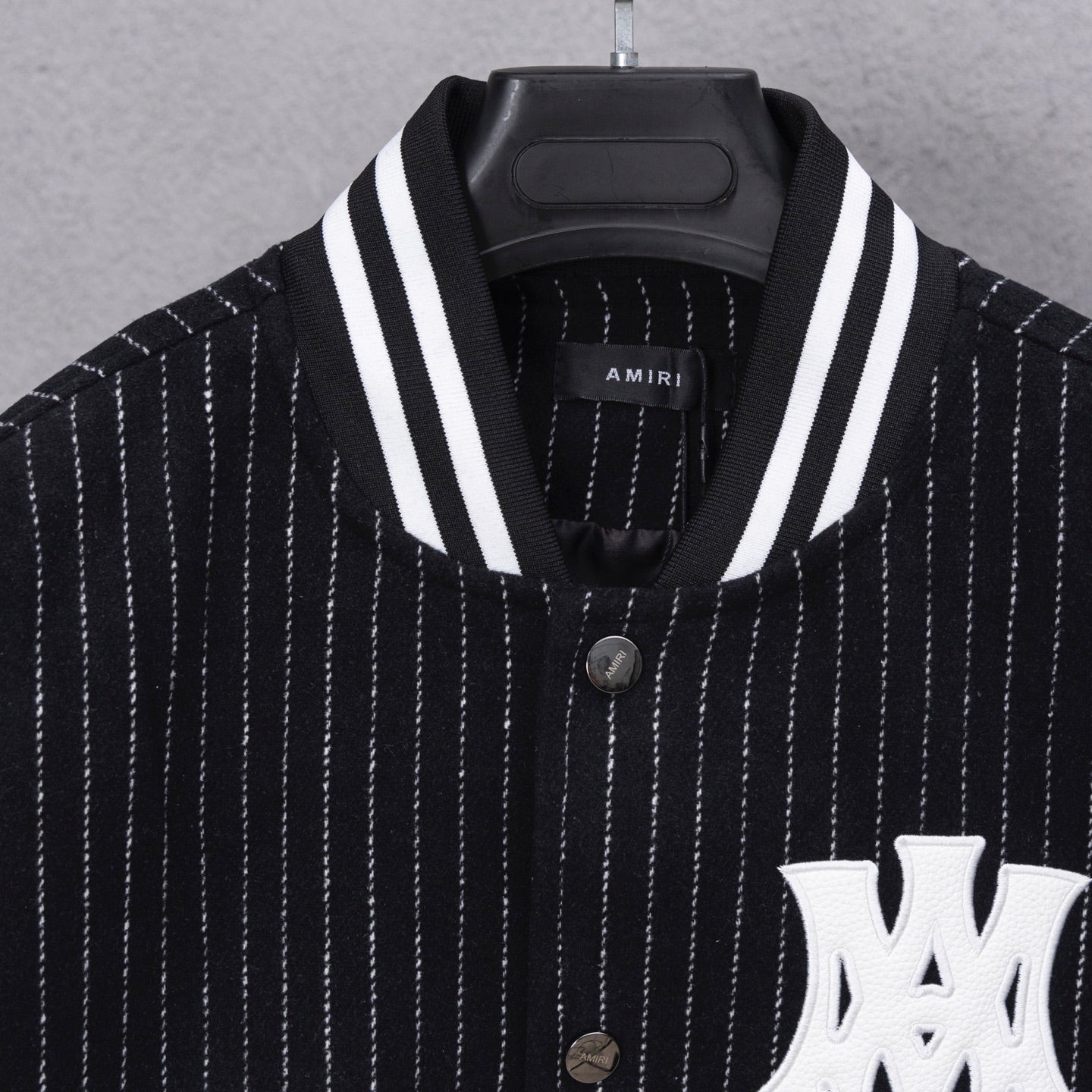Pinstripe varsity jacket with striped V-neck collar and white logo patch
