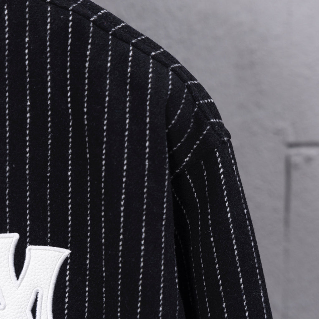 Pinstripe sleeve of dark varsity jacket with white vertical stripes