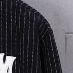 Pinstripe sleeve of dark varsity jacket with white vertical stripes