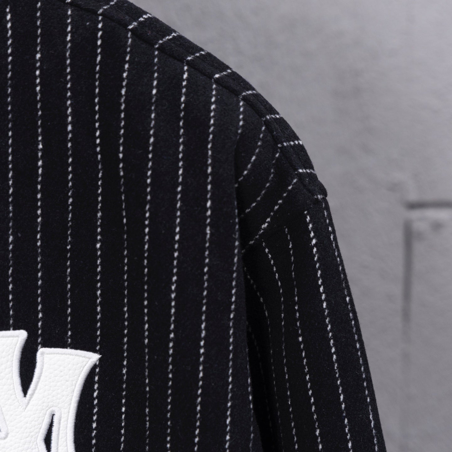Pinstripe sleeve of dark varsity jacket with white vertical stripes