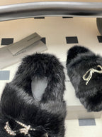 Black faux-fur slide sandals with rhinestone bow embellishment on straps