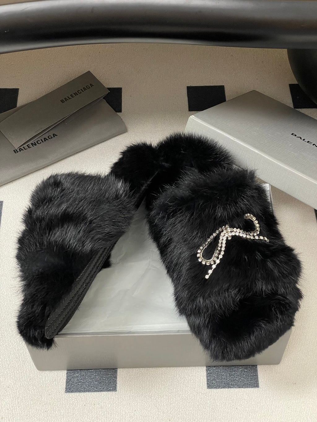 Black faux-fur slide sandals with rhinestone bow strap detail and flat sole