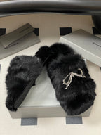 Black faux-fur slide sandals with rhinestone bow strap detail and flat sole
