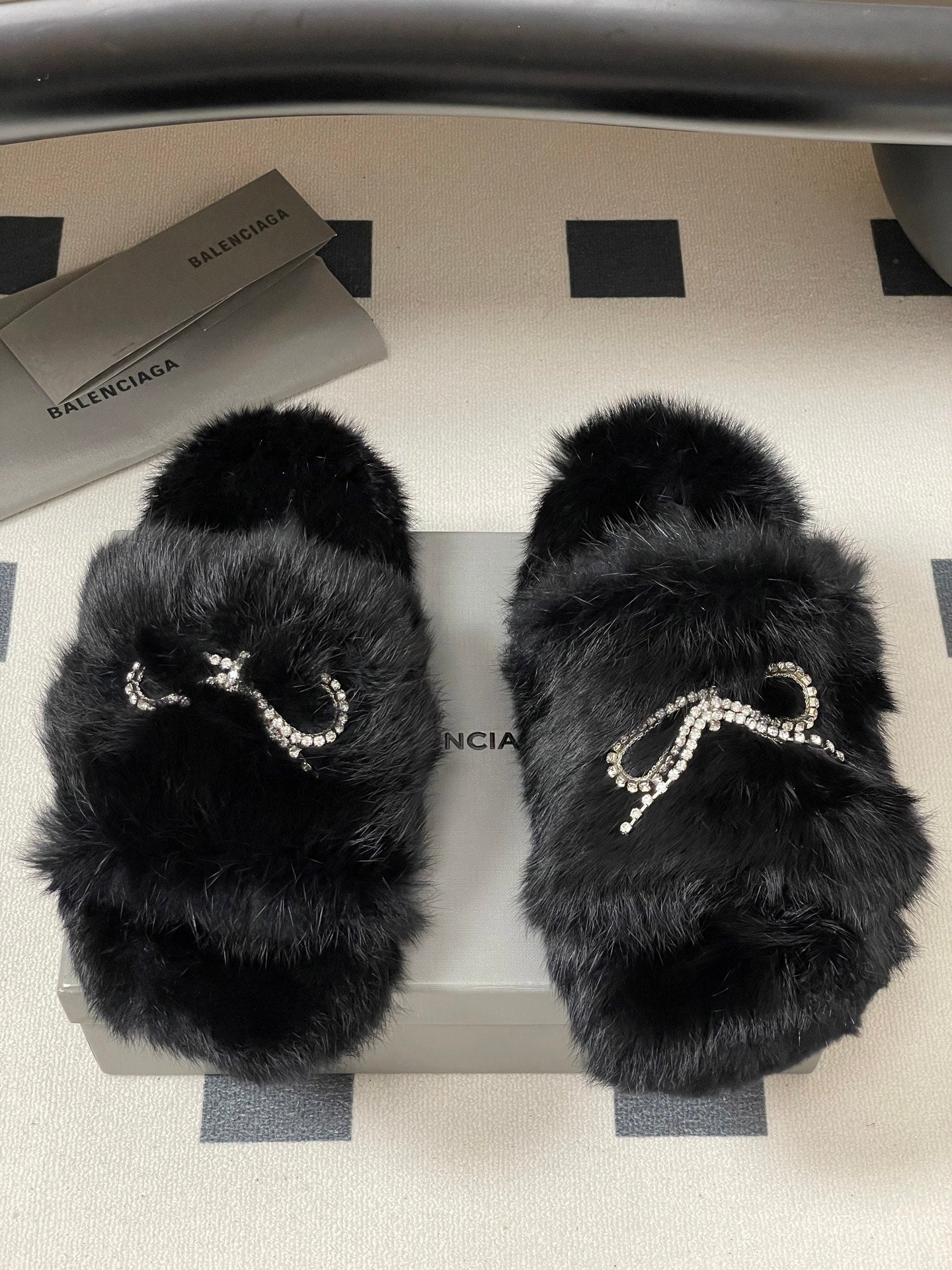 Black plush sandals with crystal bow strap detail, two slides shown