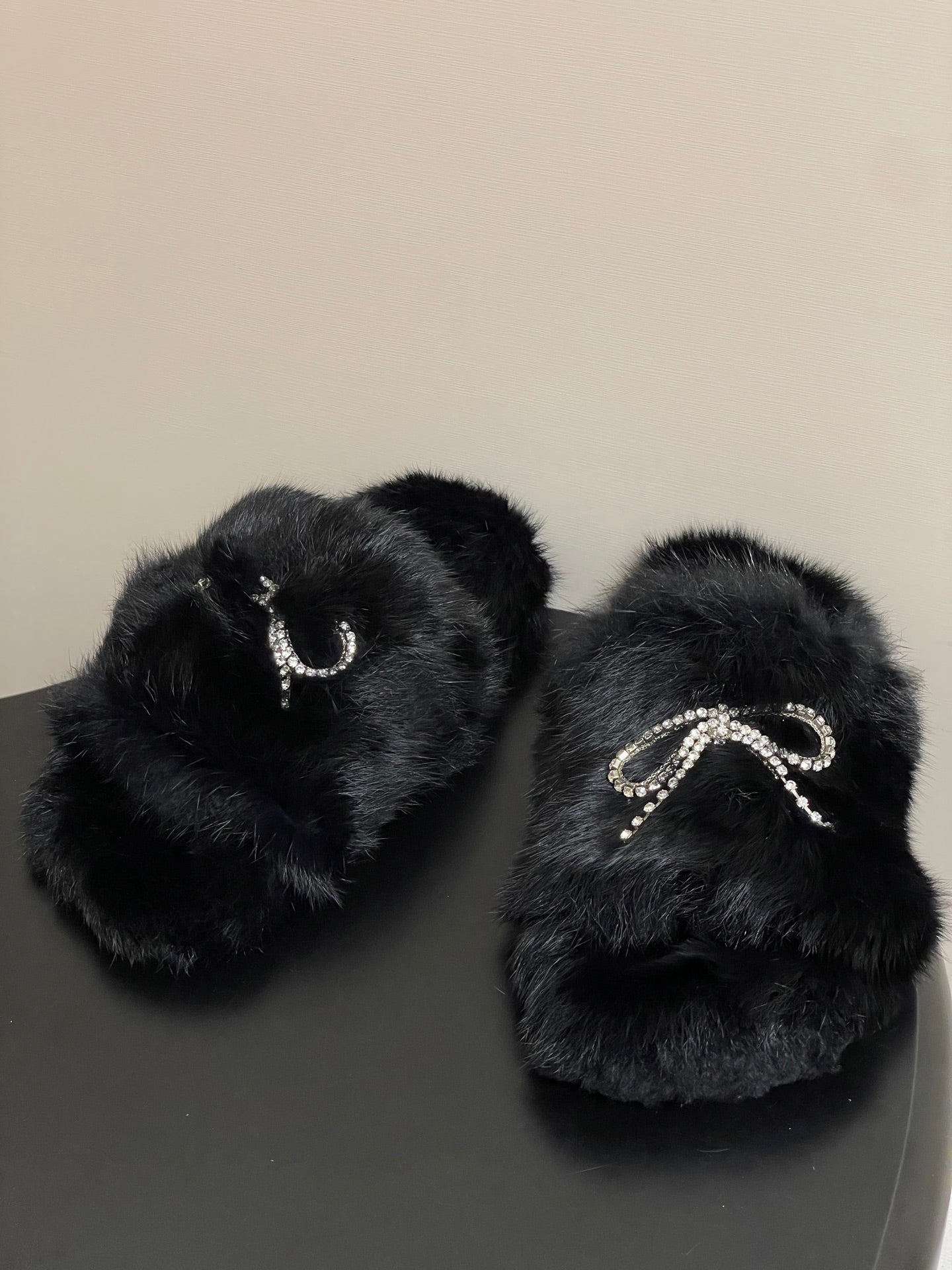 Black plush slide sandals with crystal bow-like charm on top strap