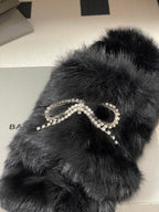 Black faux-fur slide sandals close-up, rhinestone bow strap embellishment