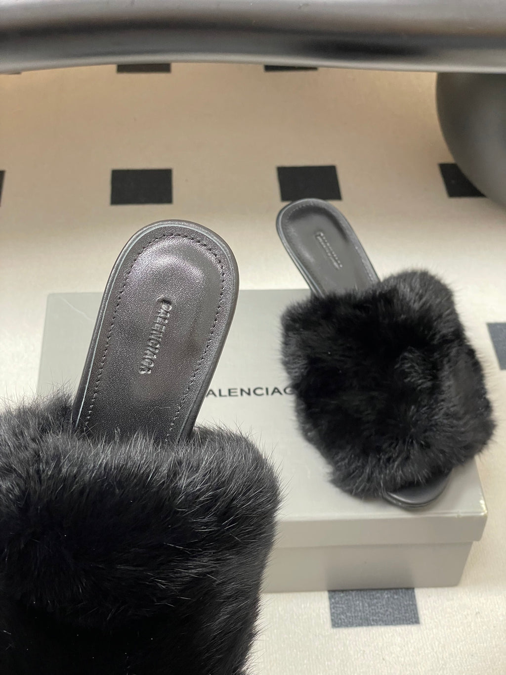 Black fur slide sandals with open toe and stiletto heel, side view
