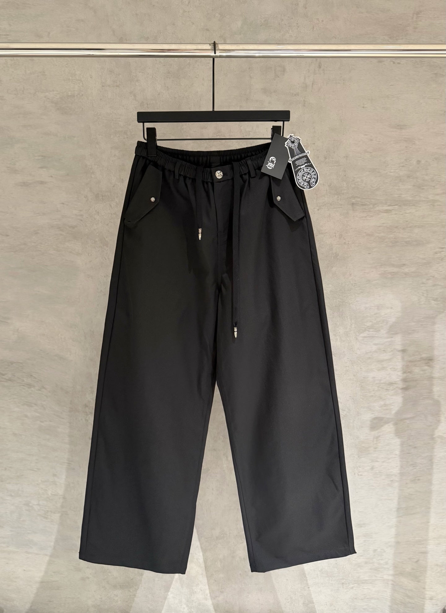 Black wide-leg pants with elastic waistband, front button, and side pockets.