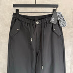 Black elastic-waist pants with two front flap pockets and small chest-like logo detail.