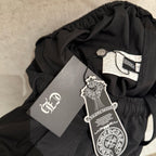 Black pants waistband with hang tags attached; elastic top edge visible.